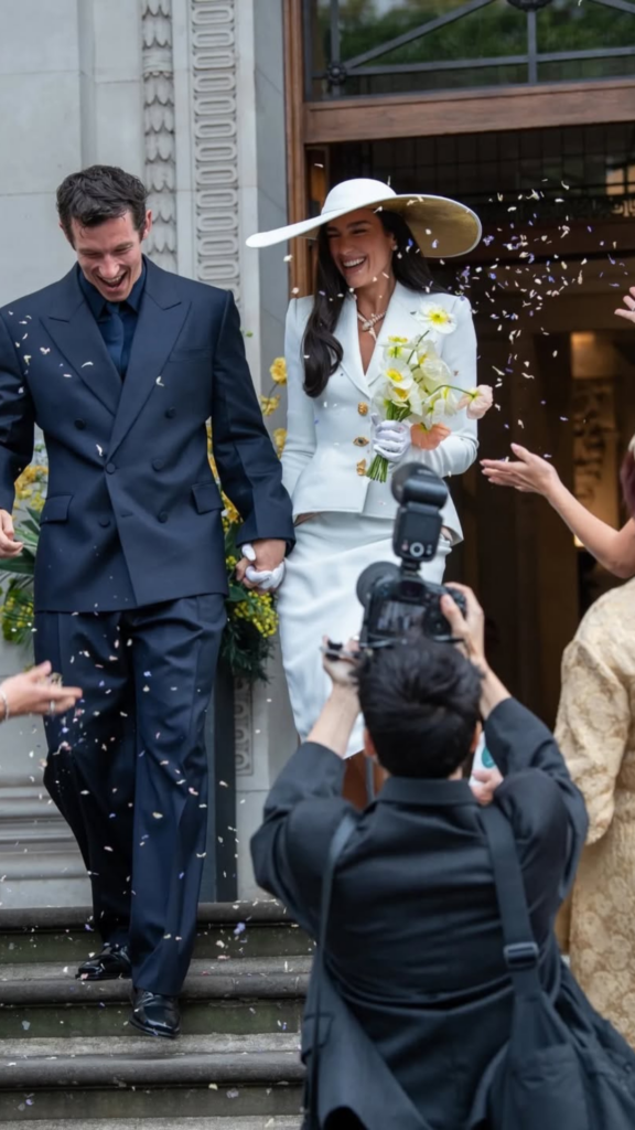 Callum Turner in navy Ferragamo suit holding Dua Lipa's hand outside Old Marylebone Town Hall London